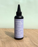 Bottle of Bekbek Makes UV Resin on a wooden surface with a light green background