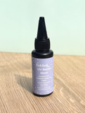 Bottle of Bekbek Makes UV Resin on a wooden surface with a light green background
