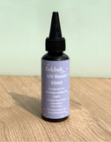 Bottle of Bekbek Makes UV Resin on a wooden surface with a light green background